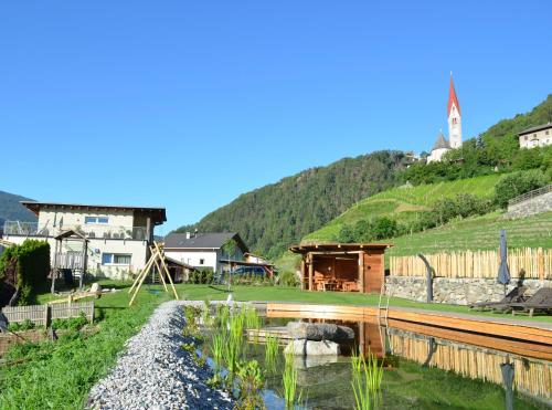 a small village with houses and a river and a mountain at Bachmannhof in Feldthurns