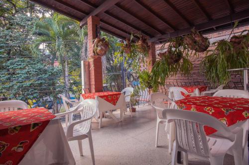 un patio con mesas y sillas rojas y blancas en Hotel Palma De Sevilla, en Medellín