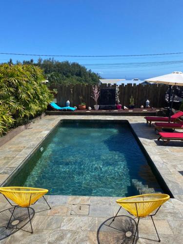 a swimming pool with two chairs and a table at La Villa Citronnier in Petite Île