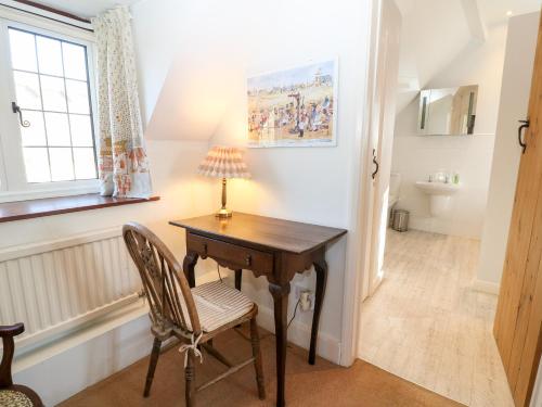 a desk with a lamp and a chair in a room at Cowfair Cottage in Chipping Campden