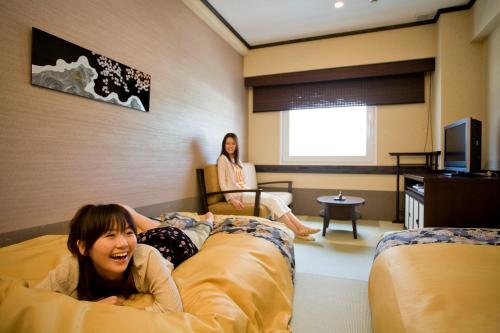 a young girl laying on a bed in a hotel room at Takayama Ouan in Takayama