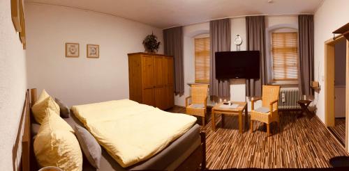 um quarto com uma cama, uma televisão e uma cadeira em Gasthof Bräustübl em Selb