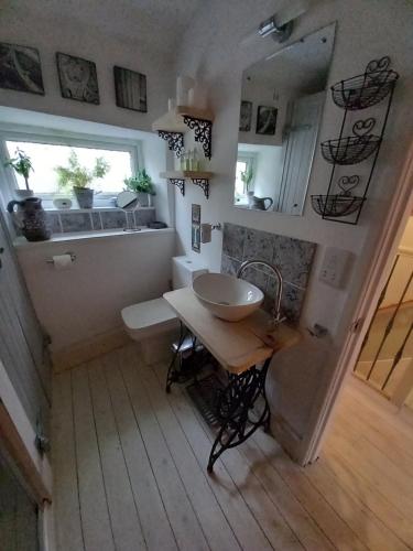 La salle de bains est pourvue d'un lavabo, d'une table et d'une fenêtre. dans l'établissement Little Pinfold Cottage, à Skipton