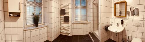 a white tiled bathroom with a sink and a mirror at Gasthof Bräustübl in Selb