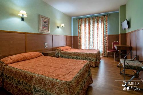 a hotel room with two beds and a television at Hotel Pio XII Jumilla in Jumilla