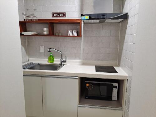 a small kitchen with a sink and a microwave at Hotel Gongjicheon in Chuncheon