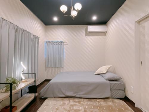 a white bedroom with a bed and a chandelier at Alo BnB 2 - Near NIPPORI, YANAKA GINZA, UENO, SENSOJI - Self check-in in Tokyo