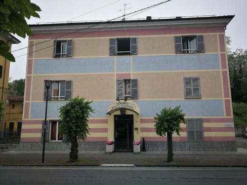 a colorful building with a door and two trees in front at ALBERGO DELLA STAZIONE in Cairo Montenotte