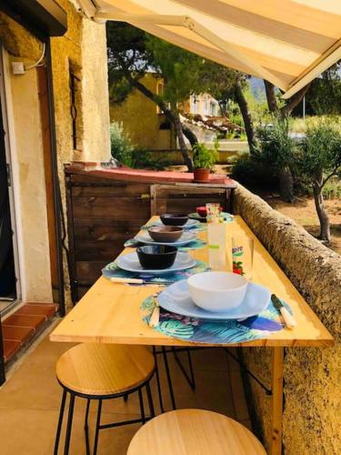 une table en bois avec des bols et des assiettes dans l'établissement Beau et confortable 2 pièces vue mer/maquis, à Lumio