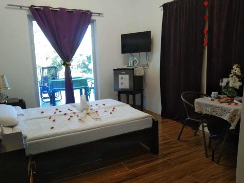 Couple room in Final Destination Resort في Bolinao: غرفة نوم مع سرير مع بتلات ورد حمراء عليه