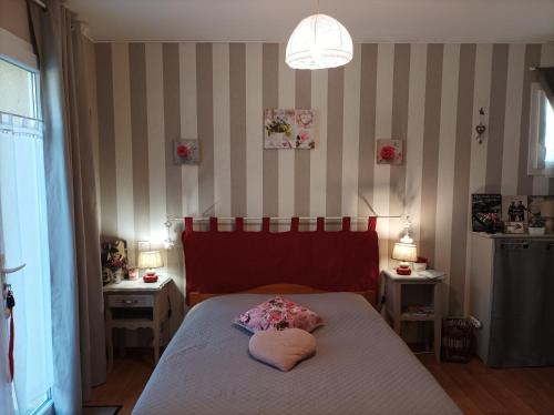 a bedroom with a bed with a pink pillow on it at Le nid de mésanges in Chauffour-sur-Vell