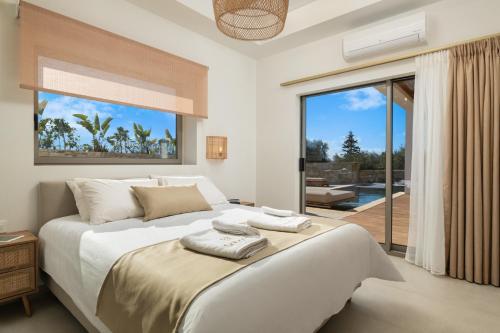 a bedroom with a large bed and a large window at Sohora twin Villas in Xirostérnion