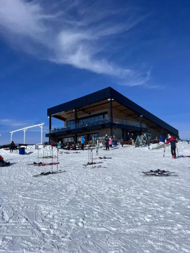 a building in the snow with skis in front of it at Mavrovo Square " Villas & Apartment " in Mavrovo