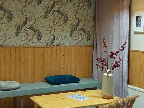瓦爾考斯的住宿－Residenssi Tuuli，一个带桌子的长凳和一个花瓶的房间