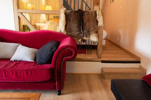 a red couch sitting in a living room next to a staircase at Gîte de la Grange in Saint-Pardoux