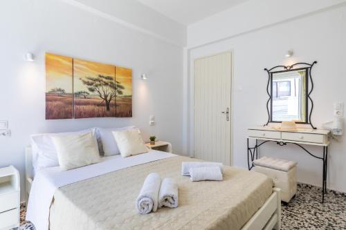 Un dormitorio blanco con una cama con toallas. en Marialena Rooms, en Skopelos Town