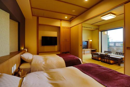 a hotel room with two beds and a television at Onyado Shikishima-kan in Kotohira
