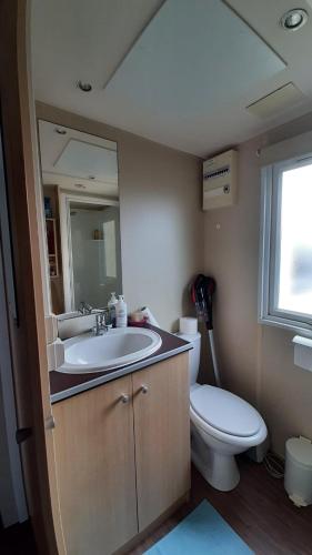 une salle de bain avec un lavabo, des toilettes et un miroir dans l'établissement mobile home la Yole 4 étoiles au calme 6 personnes, à Saint-Jean-de-Monts