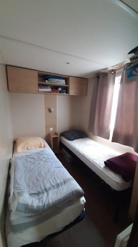 deux lits dans une petite pièce avec une fenêtre dans l'établissement mobile home la Yole 4 étoiles au calme 6 personnes, à Saint-Jean-de-Monts