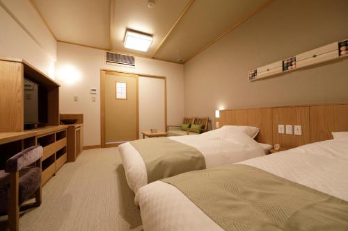 a hotel room with two beds and a flat screen tv at Onyado Shikishima-kan in Kotohira