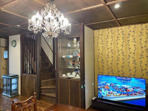 a living room with a tv and a chandelier at 浪漫宿花町 in Mitarai