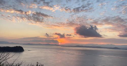 a sunset over a body of water with clouds at 浪漫宿花町 in Mitarai