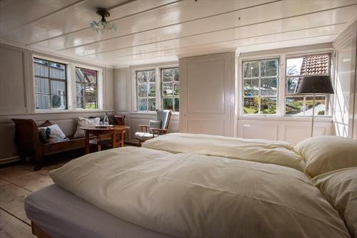 a bedroom with two beds and a table and windows at Gasthaus Rössli in Trogen