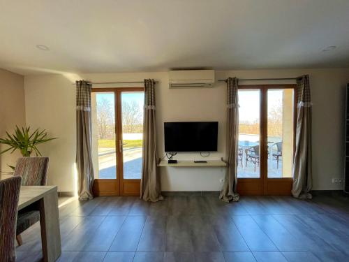 a living room with a television and sliding glass doors at Maison spacieuse avec grand jardin et parking à 20min de Lyon in Simandres