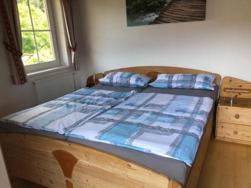 a wooden bed with a blue and white quilt on it at Sonnenchalet mit Sauna in Kötschach