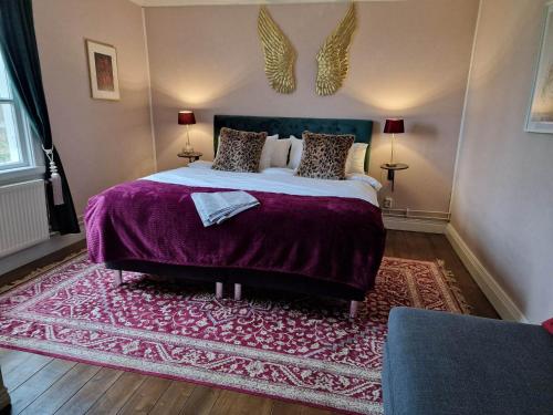 um quarto com uma cama grande e um cobertor roxo em Alstrums gård em Killstad