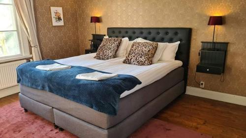 Un dormitorio con una cama grande con una manta azul. en Alstrums gård en Killstad