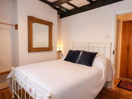 um quarto com uma grande cama branca e um espelho em The Pepper Pot em Lympstone