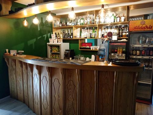 a bar with a wooden counter and a green wall at Gamma Hotel in Līvāni