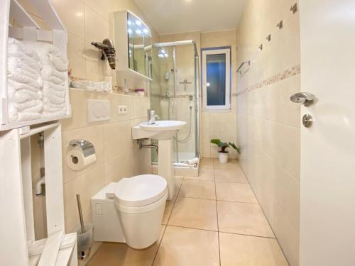 Baño blanco con aseo y lavamanos en 2 Zimmer Apartment, 70 qm, max 4 Pers, private Terasse, 2 Parkplätze, Internet 250 MBit, en Gärtringen