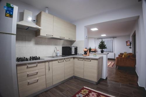 a kitchen with white cabinets and a living room at Cabana Stânceni in Drăgoiasa