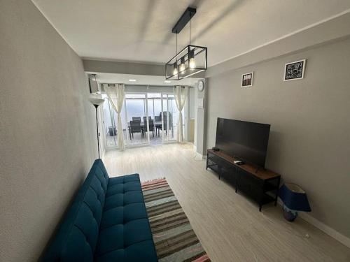 un soggiorno con divano blu e TV a schermo piatto di Apartamento T2 com terraço a 100 metros da praia a Carvoeiro