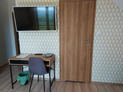 a desk with a chair and a television on a wall at Barwald Hills - jacuzzi i piękny widok na Babią Górę i Beskidy in Wadowice