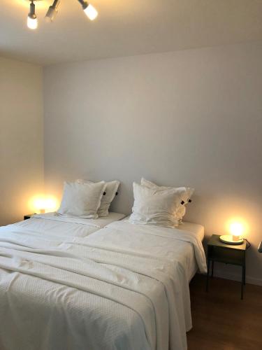 Un dormitorio con dos camas con sábanas y almohadas blancas. en White Princess - Lehouck, en Koksijde