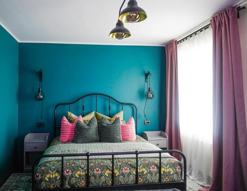 ein blaues Schlafzimmer mit einem Bett mit bunten Kissen in der Unterkunft Apartment Secret in Jonava