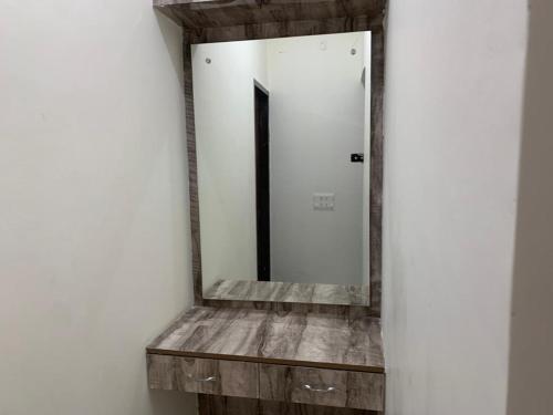um espelho numa parede com uma prateleira de madeira em Staywell360 em Chandīgarh