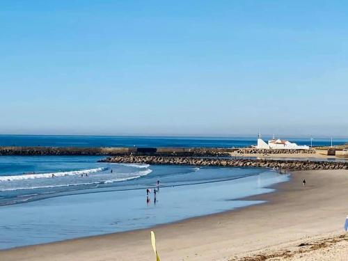uma praia com pessoas andando na areia e no oceano em Alamedastudio em Vila do Conde