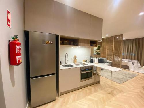 a kitchen with a stainless steel refrigerator and a living room at Alamedastudio in Vila do Conde