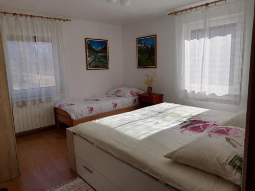 a bedroom with two beds and two windows at Apartment Vida in Bovec