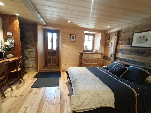 a bedroom in a log cabin with a bed and a desk at Atelier des Sapins Blancs (chambre double) in Vacheresse