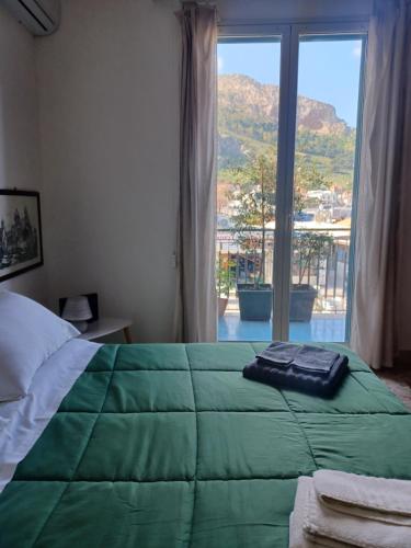 ein Schlafzimmer mit einer grünen Bettdecke und einem großen Fenster in der Unterkunft La casetta al mare in Palermo