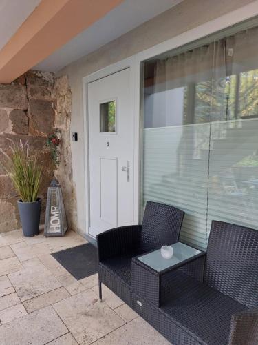 a porch with two chairs and a table and a door at Ferienwohnung "Alte Mühle" in Jena