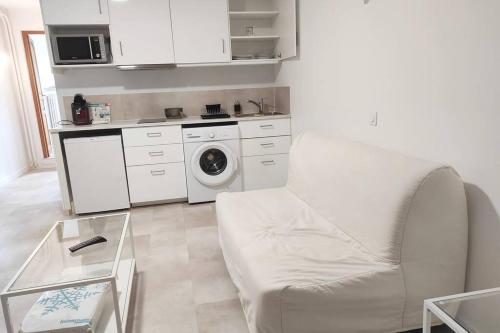 une cuisine blanche avec un lave-linge et un canapé blanc dans l'établissement Votre deux pièces à Amnéville, à Amnéville