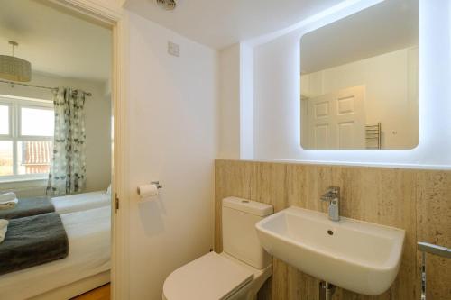 a bathroom with a toilet and a sink and a bed at Admiral's Rest in Aldeburgh