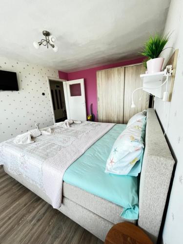 una camera con un grande letto e pareti rosa di Апартамент във вила Артемида a Varna