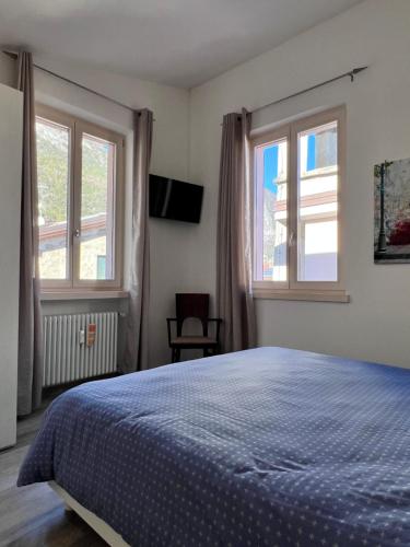 - une chambre avec un lit bleu et 2 fenêtres dans l'établissement Fiore in Centro Riva, à Riva del Garda